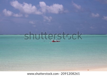 Morning in the Maldives, a man and a woman are sailing on a kayak along the coast of the Indian Ocean with white sand, corals in azure water against a blue sky with clouds.