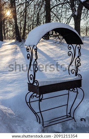 metal brazier with a canopy covered with snow stands in the park. High quality photo