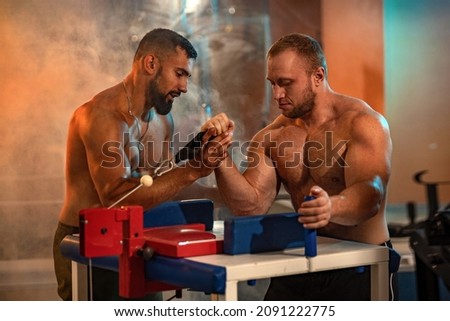 The Armwrestling. Two strong athletes in the gym have a train in arm wrestling. Bodybuilders armwreslers in athletic training room