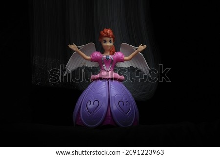 colorful Light painting in front and behind the beautiful angel doll on the black background