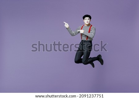 Full size body length young mime man with white face mask wears striped shirt beret pointing aside on workspace area copy space mock up isolated on plain pastel light violet background studio portrait