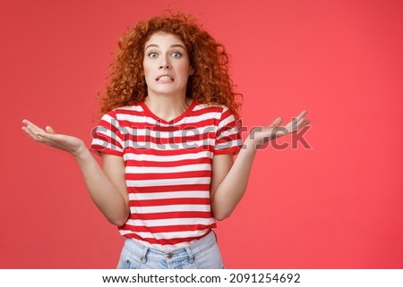 Yikes how should I know. Unaware worried awkward cute redhead curly girl clench teeth smirking uncertain panic cannot answer popping eyes confused shrugging hands spread sideways full disbelief Royalty-Free Stock Photo #2091254692