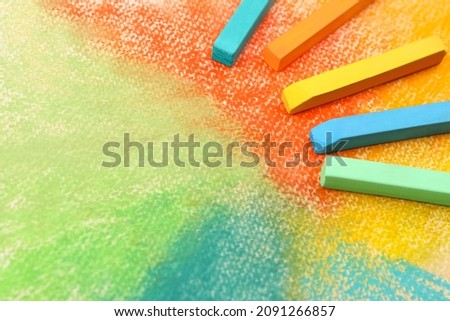 Colorful pastel chalks on abstract drawing, above view. Space for text