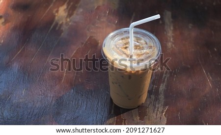 Iced coffee, plastic cup (cold drink) on wooden table nature background