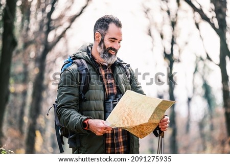 Image of man hiking and looking at map.