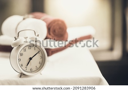 Bath towel and alarm clock on the table in the bathroom blurred background. Regime day, morning procedures and personal care, health care, health hygiene