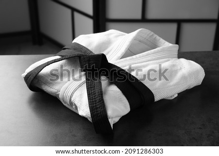 Martial arts uniform with black belt on grey stone table indoors Royalty-Free Stock Photo #2091286303