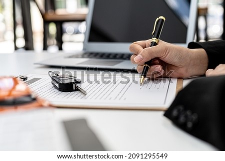Car rental company employees are checking the contract before sending the car to the customer to rent the car, preparing the contract for the customer to sign the rental agreement. Car rental concept. Royalty-Free Stock Photo #2091295549