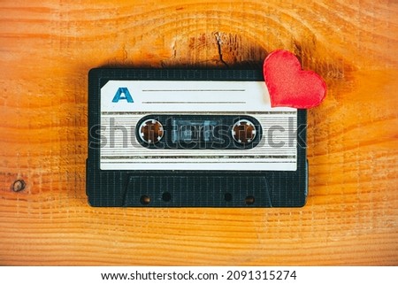 Old Audio Tape Cassette with a Red Heart on the Wooden Planks Background