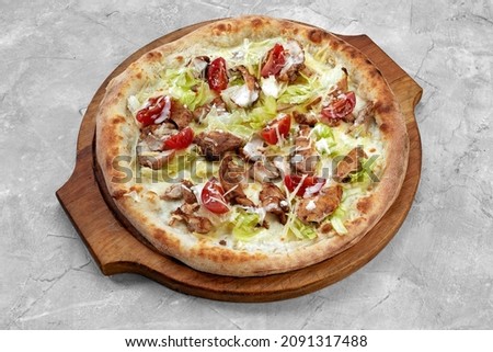 Delicious pizza Caesar style with white sauce, chicken, parmesan, egg, cherry tomatoes and fresh lettuce at wooden background. Restaurant pizzeria menu with delicious taste pizza Caesar.
