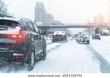Scenic view snow covered city highway slippery road drive cars moving fast speed motion. Snowfall danger blizzard bad winter weather conditions. Urban cold snowy day snowstrom town background Royalty-Free Stock Photo #2091330790