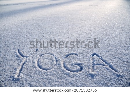 The word yoga is written in the snow. Winter yoga in the morning sun. a minimalist picture of Zen Buddhism. Peace and tranquility. High quality photo