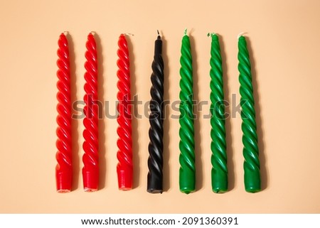 Kwanzaa African American celebration. Seven red, black and green candles on a natural beige background. Symbols of African heritage.