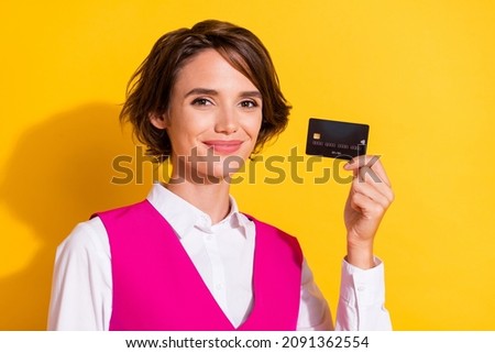 Photo of cute charming young lady wear pink suit smiling holding bank card isolated yellow color background