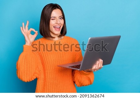 Portrait of attractive cheerful skilled girl using laptop showing ok-sign winking isolated over bright blue color background Royalty-Free Stock Photo #2091362674
