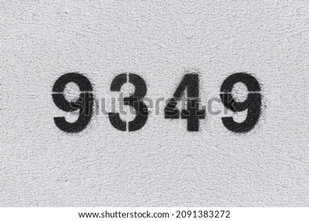 Black Number 9349 on the white wall. Spray paint. Number nine thousand three hundred forty nine.