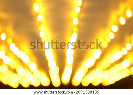 Golden festive background. Blurred yellow holiday lights in perspective