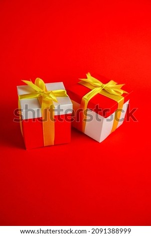 Two red and white gift package boxes with gold ribbon on red background