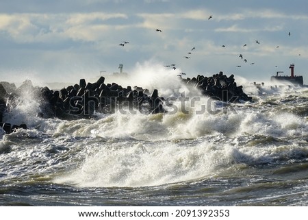 coastal storm in the Baltic Sea, big waves crash against the concrete breakwater at the port entrance Royalty-Free Stock Photo #2091392353