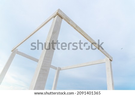 Wooden cubic structure on a blue sky background. The frame of a white rectangle in perspective. Made of timber and planks, the white structure aspires to the sky.