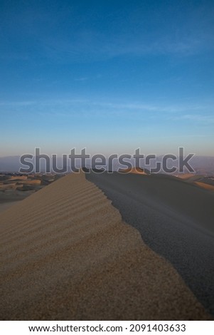 Sunset behind sand dunes in huacachina peru after tourists sand board and rode buggy taking pictures for social media.