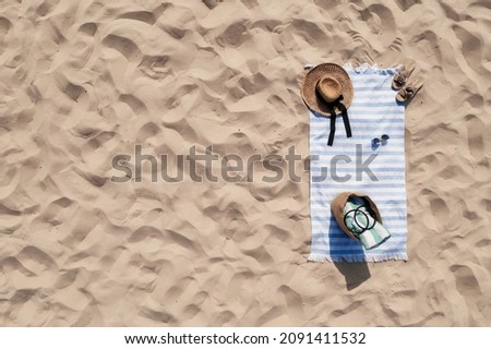 Towel with beach accessories on sand, top view. Space for text Royalty-Free Stock Photo #2091411532