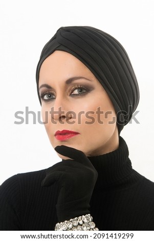 elegant woman made up and dressed in black with turban and gloves on a white background with copy space