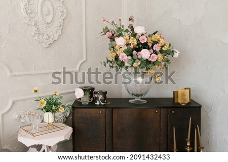 Classic bedroom interior. A brown wooden chest of drawers, flowers in a glass vase, and a white bedside table Royalty-Free Stock Photo #2091432433