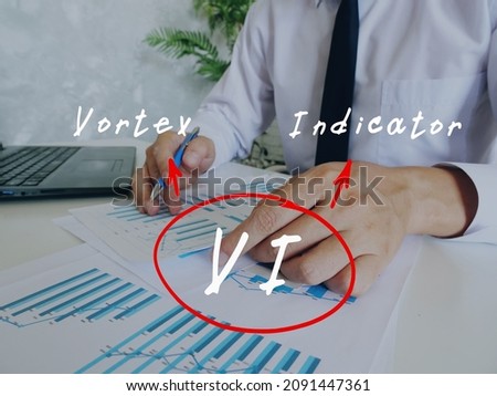 Financial concept about VI Vortex Indicator with handwritten abbreviation.Busy businessman under stress due to excessive work on background.

