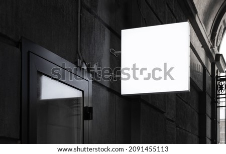 Empty square illuminated street sign near the entrance to the building. Mockup, place to insert a logo or design