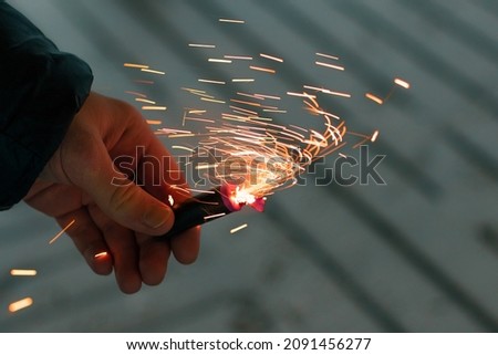 Burning Firecracker with Sparks. Guy Holding a Petard in a Hand. Loud and Dangerous New Year's Entertainment. Hooliganism with Pyrotechnics. Noise of Firecrackers in Public Places Royalty-Free Stock Photo #2091456277