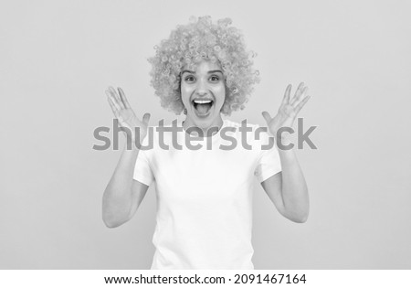 extremely happy funny girl with fancy look wearing orange hair wig on yellow background, happiness