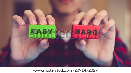  The Choice Of Difficult Or Simple Ways.Man holding EASY or HARD block.Scale option decision challenge green "EASY" and red "HARD" .Choose, decide, select for success, antonyms word.exams, education. Royalty-Free Stock Photo #2091472327