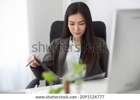 A business woman or female accountant looking at the financial report on a binder file at her modern office space. Royalty-Free Stock Photo #2091526777