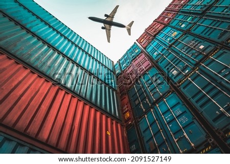 Freight airplane flying above overseas shipping container . Logistics supply chain management and international goods export concept . Royalty-Free Stock Photo #2091527149