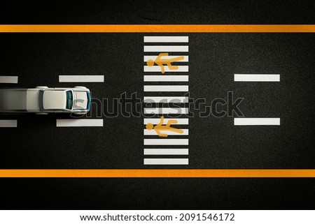 Top view of tiny model car speeding on black highway with crosswalk