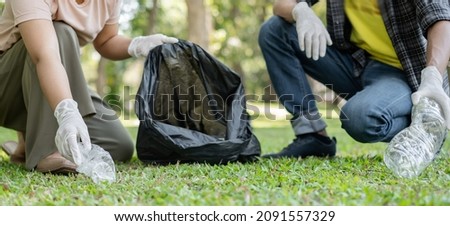garbage collection, volunteer team pick up plastic bottles, put garbage in black garbage bags to clean up at parks, avoid pollution, be friendly to the environment and ecosystem. Royalty-Free Stock Photo #2091557329