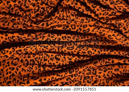 Leopard print fabric. Orange with black spots. Folds on the fabric.