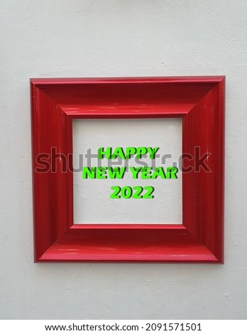 Red striped wooden square shape frame over white background with green Happy New Year 2022 lettering.