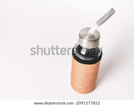 Photo of reusable glass water bottle against white background.  Environment friendly concept.
