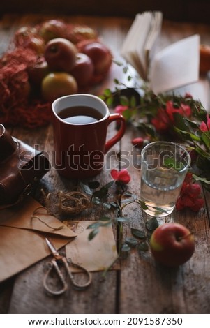            A mug of tea on a wooden background, old envelopes, flowers in retro style.                    