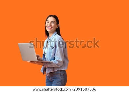 Young woman with laptop on color background