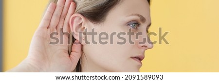Deaf-mute woman holding her hand near ear. Women secrets concept Royalty-Free Stock Photo #2091589093