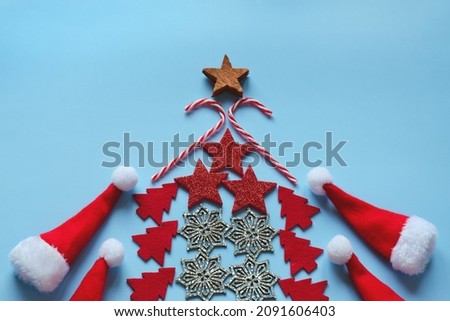Flat lay of Christmas tree made from colorful decorations against blue background. Top view. New Year mood. Greeting card. Party and holiday celebration concept.