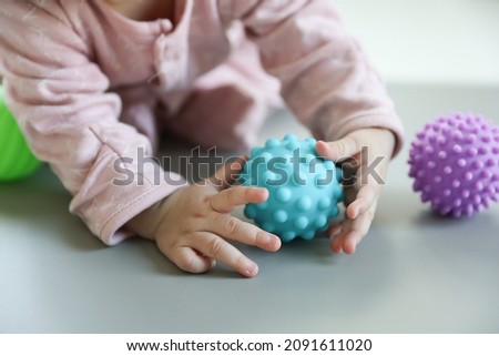 Taking photo of Asian baby hands touching high quality of light blue plastic ball.