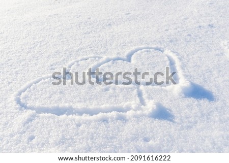 Couple drawn heart shape in the fresh snow.