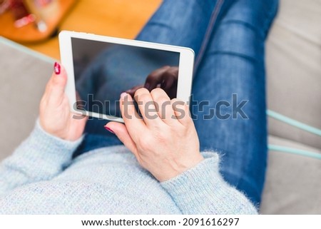 Woman using tablet and sitting on sofa,or couch.Woman using tablet at home in living room. Mockup for your text.Selective focus.