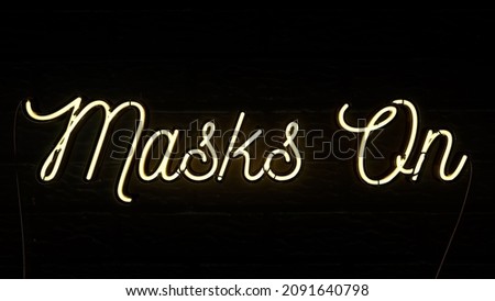 Neon sign on a brick wall background saying Masks on warning people to put on a mask due to the coronavirus  covid-19 pandemic, 