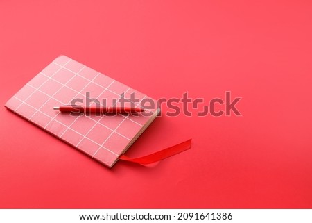 Notebook with bookmark and pen on color background