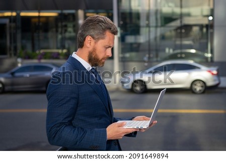 Businessman with notebook outdoor. Confident business expert. Handsome man in suit holding laptop against office background.